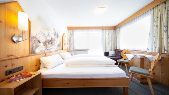 A cozy bedroom with two wooden twin beds. Large windows provide plenty of daylight and a welcoming atmosphere. - Haus Alpenstern - Sölden