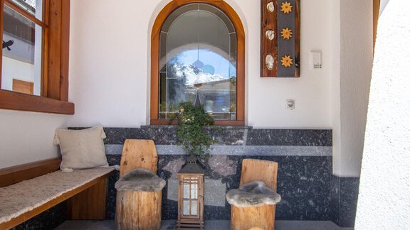 A stylish entrance area with bright windows and wooden details. The wooden seating invites you to linger. - Haus Alpenstern - Sölden