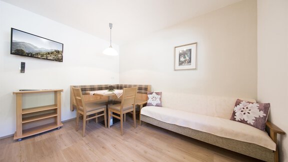 A cozy living space with a dining table and chairs. A television and a picture hang on the wall. - Haus Christian - Sölden