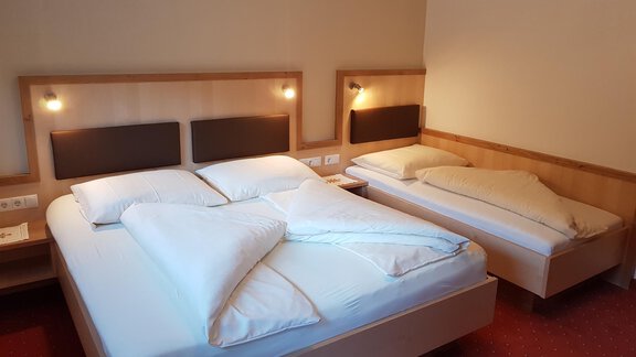 A cozy hotel room with two beds. The walls are light and the lighting creates a pleasant atmosphere. - Haus Christian - Sölden