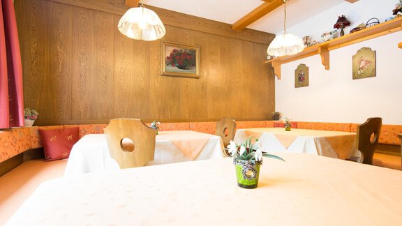 A cozy restaurant with wooden walls and tables covered with white tablecloths. The walls are adorned with pictures and decorative elements. - Haus Christian - Sölden