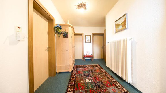 A bright hallway with a long carpet. On the walls, there are doors and a decorative picture. - Haus Christian - Sölden