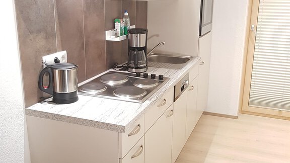 A modern kitchen with bright cabinets and a stove. It is well-equipped and has plenty of natural light. - Haus Christian - Sölden