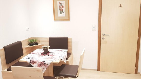 A cozy dining area with a wooden table and chairs. A picture hangs on the wall, and a small plant sits on the table. - Haus Christian - Sölden