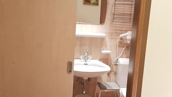 A small bathroom with a sink and a toilet. The walls are tiled in light colors and there is a towel rack. - Haus Christian - Sölden