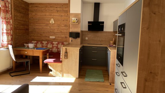A modern kitchen with wooden cladding and a cozy seating area. The room is bright and inviting, with a large window that lets in daylight. - HAUS ERIKA apartments - Sölden