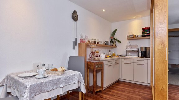 A cozy kitchen with a dining table and modern kitchen cabinets. The room is bright and inviting. - Haus Fontana - Sölden