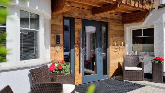 An inviting entrance area with wood paneling and modern furniture.  
Colorful flowers and a well-maintained carpet create a cozy atmosphere. - Haus Gondelblick - Sölden