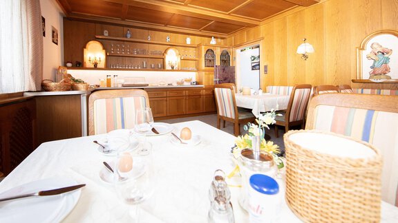 A cozy dining room with wooden walls and a table set for breakfast. In the background, the bar and some decorative elements are visible. - Haus Montjola - Sölden