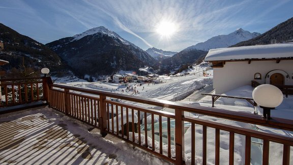 A picturesque snowy landscape with mountains and a ski slope. The sun shines over the scene, creating a bright, inviting atmosphere. - Haus Montjola - Sölden