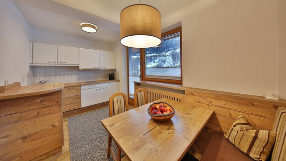 A modern kitchen with a wooden dining table. The room is bright and cheerful, with large windows and natural light. - Haus Söldenblick - Sölden