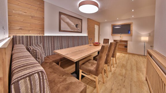 A modern dining room with a large wooden table and comfortable chairs. The warm tones and stylish lighting create an inviting atmosphere. - Haus Söldenblick - Sölden
