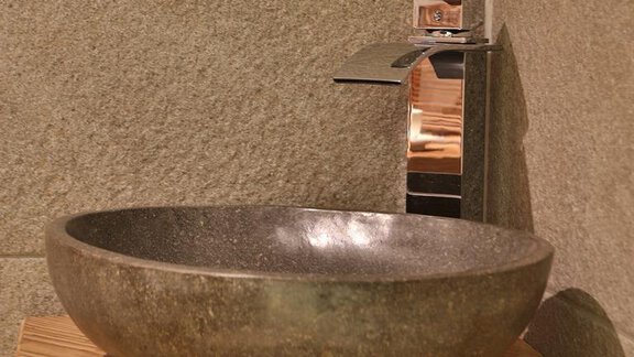 An elegant sink made of gray stone on a wooden pedestal. The modern faucet complements the simple design. - Haus Söldenblick - Sölden
