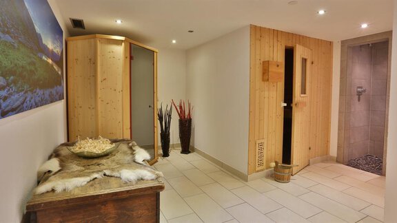 An inviting wellness area with wooden decor and modern tiles. In the background, a sauna and a shower are visible. - Haus Söldenblick - Sölden