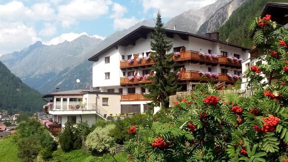 A picturesque hotel in the mountains with balconies and colorful flowers. Majestic mountains and a clear sky can be seen in the background. - Haus Söldenblick - Sölden