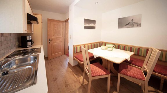 A modern kitchenette with a dining table and comfortable chairs. Soft colors and lighting create an inviting atmosphere. - Haus Sonnwend - Sölden