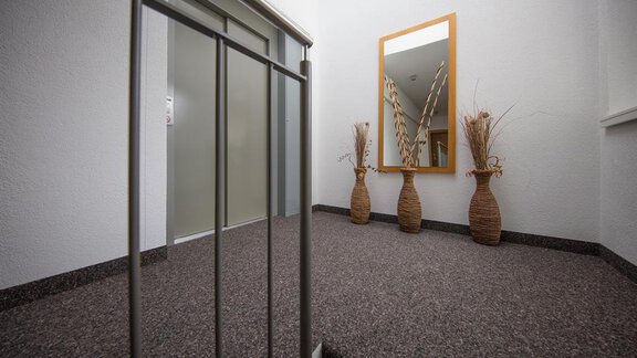 A bright entrance area with an elevator and a mirror. Two decorative vases are placed against the wall. - Haus Stefanie - Sölden