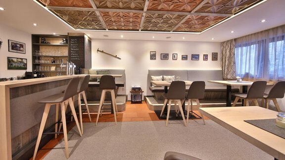 A modern restaurant with an elegant bar and stylish seating. The warm colors and the creative ceiling pattern create an inviting atmosphere. - Haus Söldenblick - Sölden