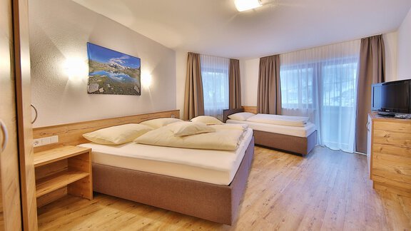 A cozy bedroom with two beds and a wooden floor.  
Large windows let in plenty of light and create a pleasant atmosphere. - Haus Söldenblick - Sölden