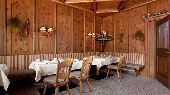 A cozy restaurant with wood paneling and an inviting atmosphere. The table is set for guests and there are numerous chairs. - Hotel Garni Ehrenreich - Sölden