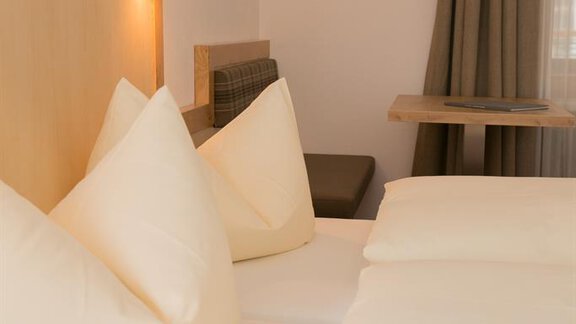 A bright room with two large beds and cozy pillows. Soft curtains and gentle lighting create an inviting atmosphere. - Hotel Garni Ehrenreich - Sölden