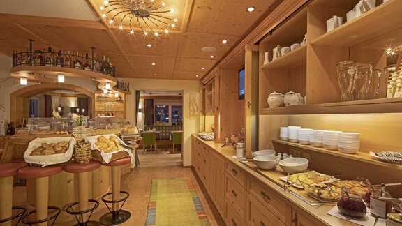 A cozy dining room with wooden decor and warm light. Fresh rolls and other treats are arranged on the buffet. - Hotelappart Peter - Sölden
