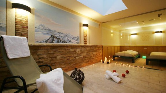 A relaxing wellness area with a lounger, soft lighting, and a mountain view on the wall. Decorative elements and tranquility create a pleasant atmosphere. - Hotelappart Peter - Sölden | © Falkner Georg