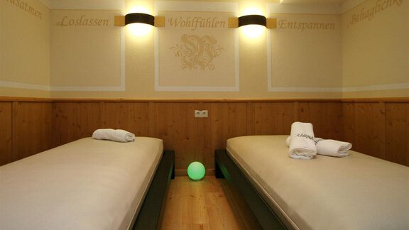 A quiet room with two single beds and towels. The walls are light and decorated with relaxing words. - Hotelappart Peter - Sölden | © Falkner Georg