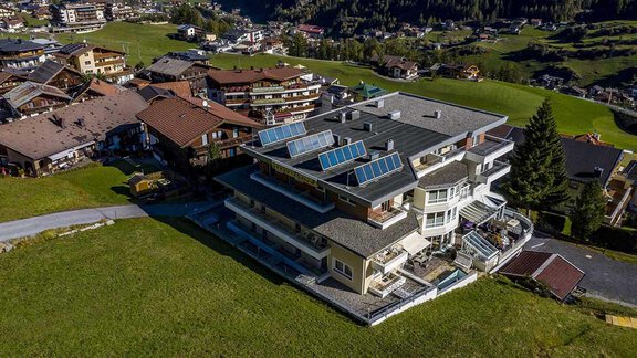 A modern house with solar panels in a picturesque mountain landscape. Surrounded by traditional chalets and green meadows. - Hotelappart Peter - Sölden