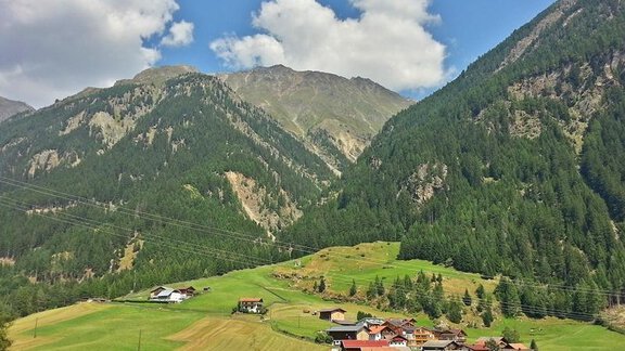 A picturesque valley with green meadows and small houses. Surrounded by majestic mountains and a blue sky with some clouds. - Landhaus Fiegl Hubert - Sölden