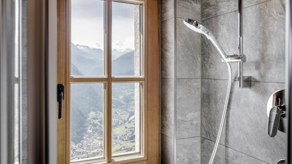 An elegant shower with a large window front that offers a stunning view of the mountains. The space is designed to be modern and inviting. - LENI MOUNTAIN CHALET - Sölden