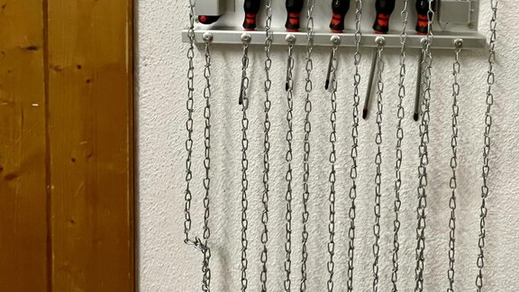 A service station with tools that are attached to a wall. The tools hang on chains and are neatly arranged. - Lutonia Appartements Sölden - Sölden