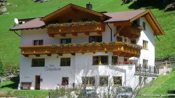 A charming house in the mountains with balconies full of flowers. The green meadow and the rocks in the background create an idyllic atmosphere. - Pension Birkenheim - Sölden