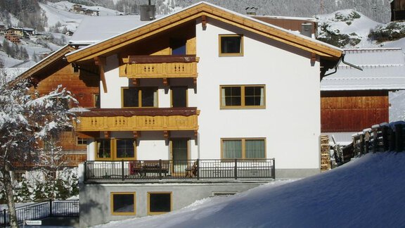A cozy house in the snow with wooden balconies. The surroundings are picturesque with snow-covered mountains and trees. - Pension Birkenheim - Sölden