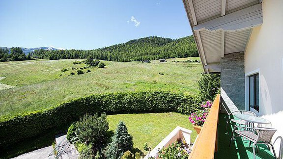 A beautiful view from a balcony overlooking a green meadow and wooded hills. The sunny landscape provides a calm and relaxing atmosphere. - Pension Charly - Sölden