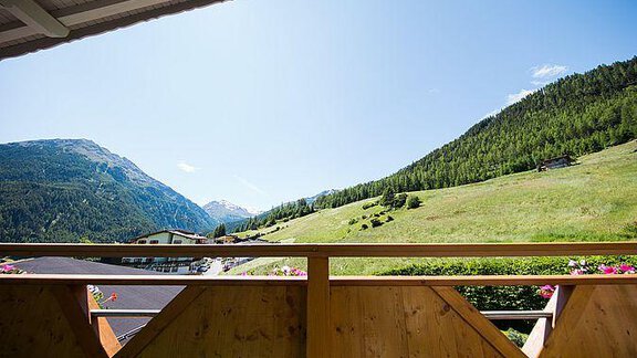 A beautiful view from a balcony of green meadows and mountains. The sky is clear and blue, perfect for a relaxing day in nature. - Pension Charly - Sölden