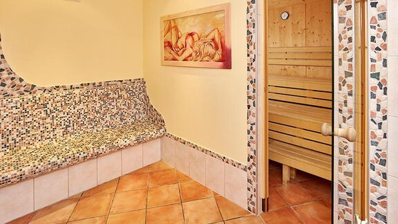 A cozy sauna area with colorful tiles and a bench. On the right is a wooden sauna. - Pension Gritsch Ewald - Sölden