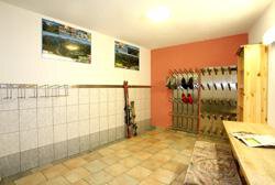 A small room with tiled floor and a wardrobe. Skis and shoes are hanging on the wall, there are also pictures of landscapes. - Pension Gritsch Ewald - Sölden