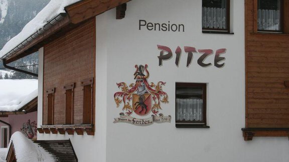 A guesthouse named "Pitze" in a snow-covered area. The building has a mix of wooden and white walls. - Pension Pitze - Sölden