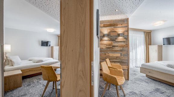 A modern room with wooden and carpeted flooring. The room is bright and cozy, with a separate living area and a view of the outdoor grounds. - Residenz Allegra - Sölden