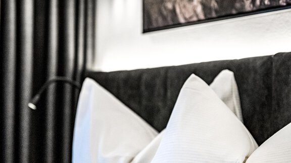 A modern hotel room with elegant cushions and a stylish lamp. In the background, an appealing piece of art can be seen. - Sonnalp Residences - Sölden