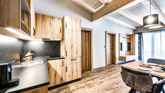 A modern kitchen with wooden cabinets and elegant surfaces. The room is bright and warmly decorated. - Sonnalp Residences - Sölden