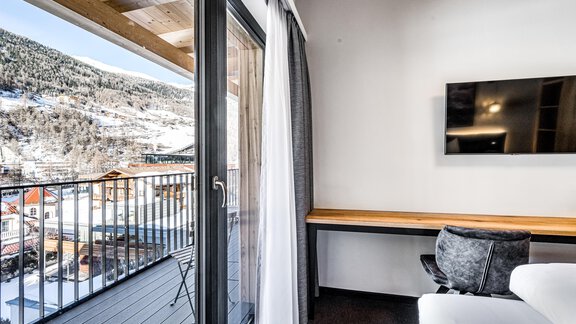 A modern living space with large windows and a view of the mountains. The balcony offers a beautiful view and the room is bright and inviting. - Sonnalp Residences - Sölden