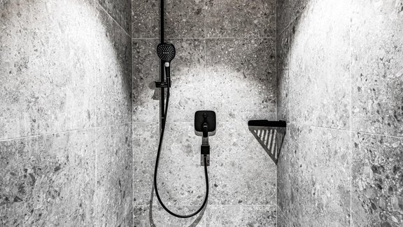 A modern shower with gray tiles and an elegant rain shower. The walls are designed simply and minimally. - Sonnalp Residences - Sölden