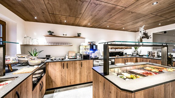 A modern breakfast bar with wooden shelves and a variety of food offerings. The room is bright and invitingly designed. - Sonnalp Residences - Sölden