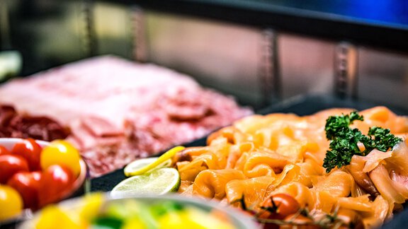 A selection of meats and freshly prepared salmon on a buffet. Accompanied by colorful tomatoes and citrus fruits. - Sonnalp Residences - Sölden