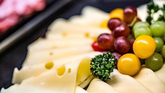 An attractively arranged plate with various types of cheese, grapes, and small tomatoes. Fresh herbs decorate the selection. - Sonnalp Residences - Sölden