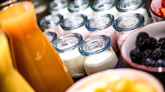 A breakfast table with yogurt in small jars and fresh fruit. Next to it are orange juice and a bowl of berries. - Sonnalp Residences - Sölden