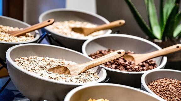 A selection of mueslis in large bowls with wooden spoons. The bowls contain different varieties, including oats and chocolate chips. - Sonnalp Residences - Sölden