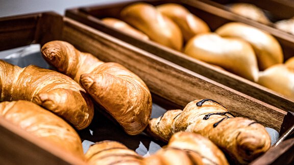 Fresh rolls and croissants in wooden bowls. The golden-brown baked goods are arranged appetizingly. - Sonnalp Residences - Sölden